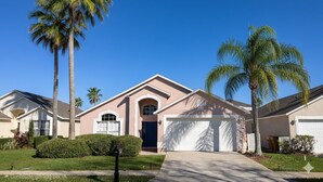 Una casa residenziale con garage, palme e un cielo azzurro limpido.