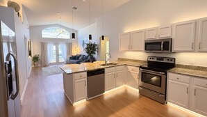 Una cucina moderna con piani in granito, elettrodomestici in acciaio inossidabile e mobili bianchi.