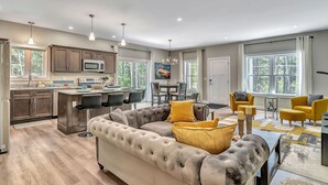 A spacious living area with a large sectional sofa, a dining table with chairs, and a kitchen area with modern appliances. - Shipbuilder’s Retreat sleeps 6, 5 minutes to Harbor (East Boothbay)