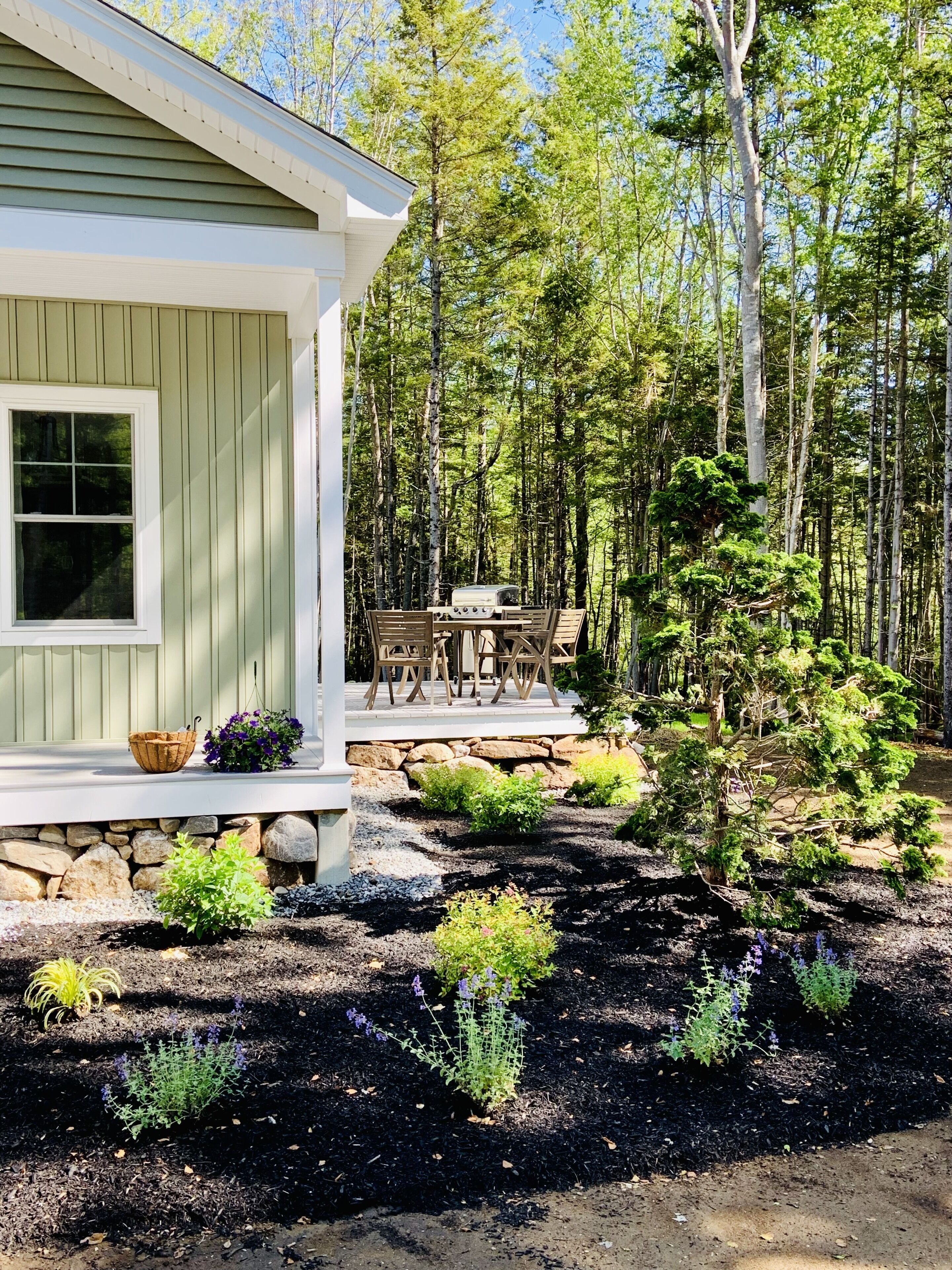 A house with a porch, outdoor seating, and a garden area with various plants.