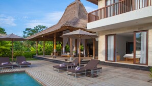 A poolside area with lounge chairs and umbrellas, a thatched-roof structure, and a modern building with large windows. - Villa Lumia - 4BR · 20m Pool · Jacuzzi · Private Chef · Rice Fields · Ubud (Ubud)