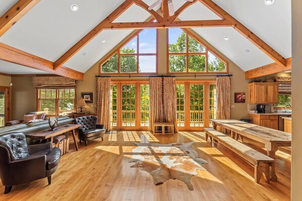 A spacious loft with high ceilings, large windows, a dining area, and a cozy seating area.
