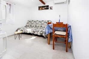 A small, well-lit room with a bed, a chair, and a table.