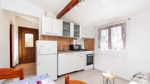 Une cuisine compacte avec des meubles blancs, un four à micro-ondes encastré, une cuisinière et un réfrigérateur.