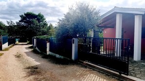 Un lotissement résidentiel fermé, avec une allée pavée menant à une maison à la façade rouge et aux colonnes blanches.