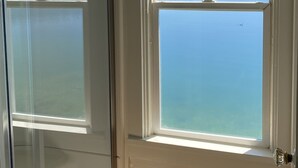 Ein Zimmer mit einem großen Fenster und Blick auf einen See sowie bewaldete Hügel.