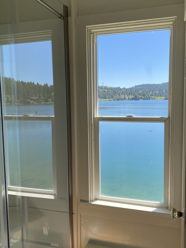 Una habitación con un ventanal que ofrece vistas a un lago y colinas boscosas.