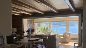 Ein großzügiger Wohnbereich mit Seeblick, ein Essbereich mit Holzkästen und eine gemütliche Sitzecke am Fenster.