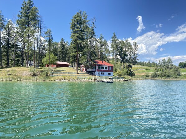 Escape to a serene lakeside retreat surrounded by lush trees and rolling hills.