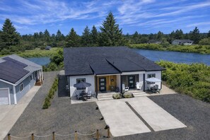 Une maison à deux étages avec un porche à l’avant, un patio couvert et une vue sur un lac.