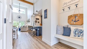 Um interior moderno com cozinha, sala de jantar e área de estar decorada com motivos náuticos.
