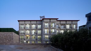 Un immeuble à plusieurs étages doté de balcons, de grandes fenêtres et d’un mur en pierre sur le côté gauche.