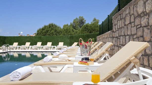 Un espace aménagé au bord de la piscine, avec des chaises longues, des serviettes et un livre.
