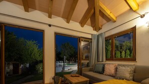 A cozy living room with a sofa, a coffee table, and a yellow throw blanket. Large windows offer a view of the outdoors. - Holiday Home Flores with Pool (Labin)