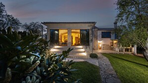 A modern house with large glass windows, a stone pathway, and a well-maintained lawn. - Holiday Home Flores with Pool (Labin)