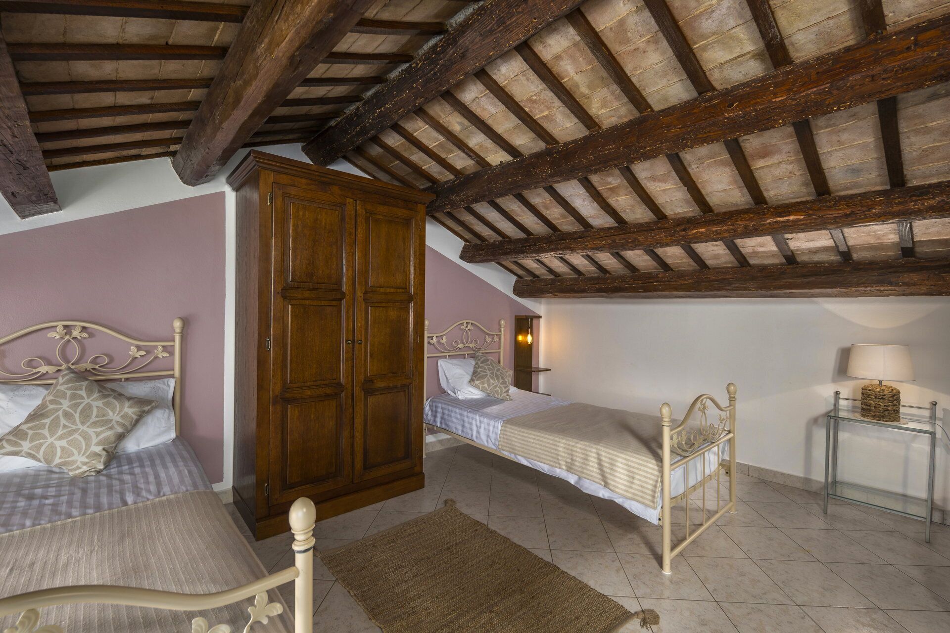 Una camera da letto con due letti, un armadio in legno e un tavolino con una lampada.
