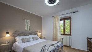 A bedroom with a bed, bedside lamps, a window with curtains, a radiator, and a ceiling fan. - Holiday Home Flores with Pool (Labin)