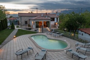 Une maison avec une piscine, un espace extérieur aménagé et une façade en pierre.