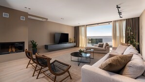 Ett modernt vardagsrum med en soffa, två fåtöljer, ett soffbord, en tv och en öppen spis.