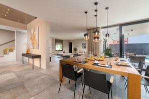 Un espace de salle à manger moderne avec une table en bois, des chaises noires et des luminaires suspendus.