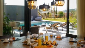 En frukostplats med utsikt över poolen, med ett matbord där frukosten serveras, solstolar och en swimmingpool.