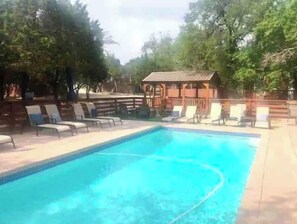 Relax by the pool surrounded by a wooden deck and shaded gazebo.