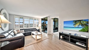 Een moderne woonkamer met een leren bank, een glazen salontafel en een flatscreen televisie.