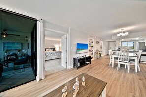 A spacious living area with a large TV, a dining table, and a kitchen area.