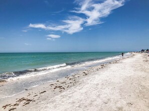 A beach with a wide sandy shore, calm sea, and a clear sky.