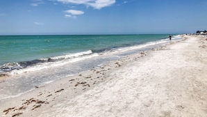 Een strand met een breed zandstrand, rustige zee en een heldere lucht.