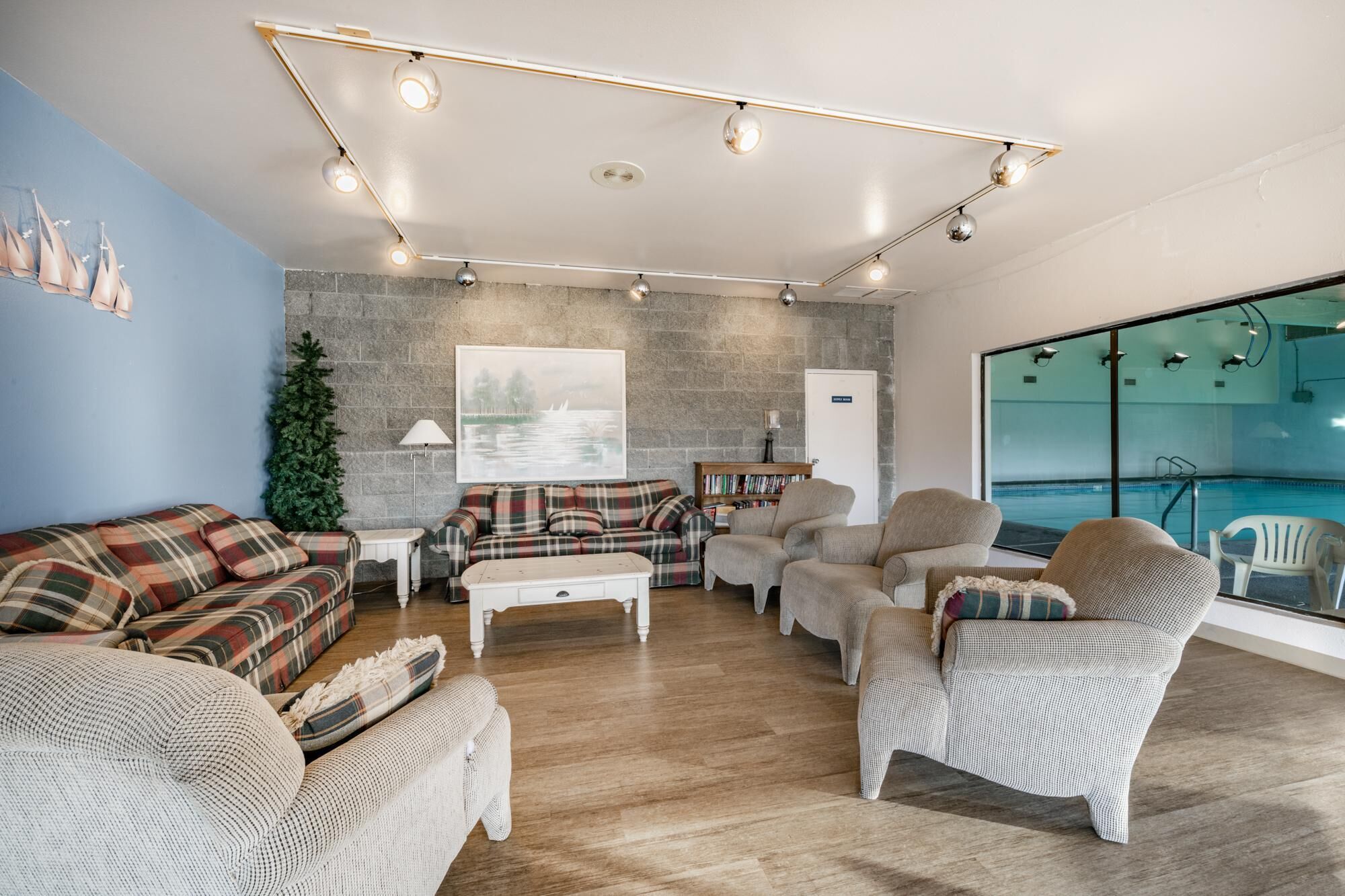 A modern living room with a fireplace, a large window overlooking a pool, and a cozy seating area with multiple sofas and armchairs.
