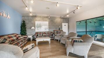 A modern living room with a fireplace, a large window overlooking a pool, and a cozy seating area with multiple sofas and armchairs.