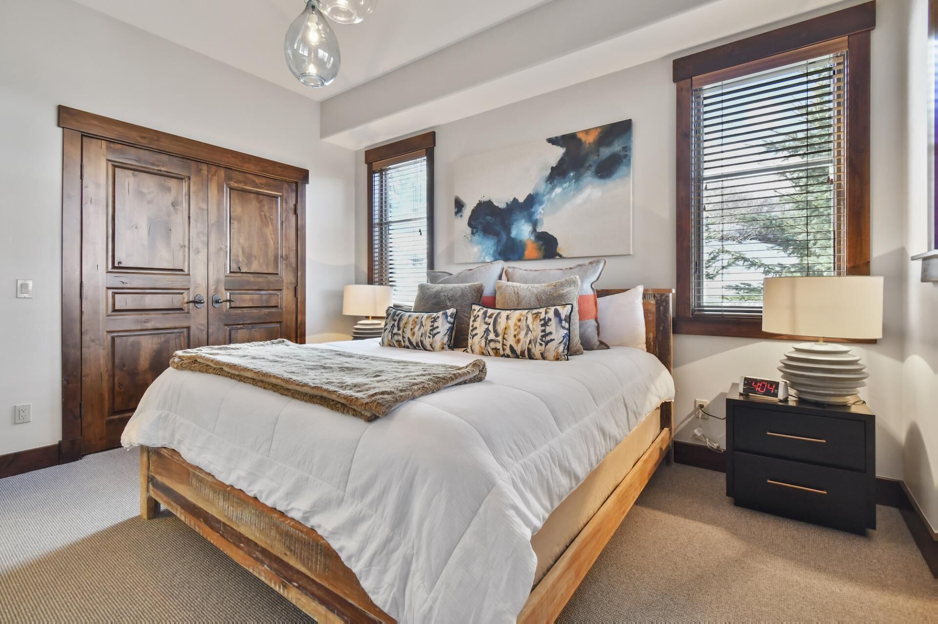 Un dormitorio con una cama grande, un armario de madera y un cuadro en la pared.