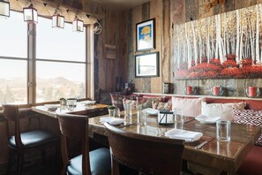 A restaurant with a rustic interior, wooden walls, and a large window offering a view of the city.