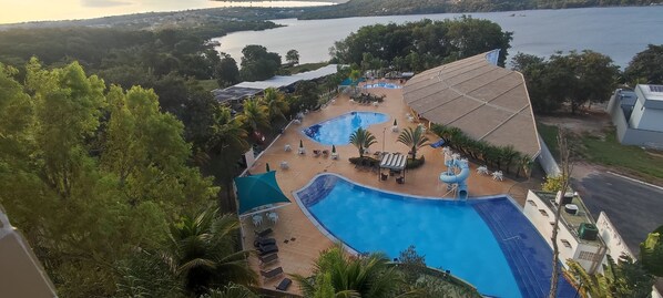 Relax by the serene lake with a swim in the resort's pool, surrounded by lush greenery and sun loungers.