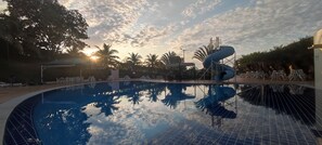 Relax by the serene pool surrounded by lush palm trees and lounge chairs.