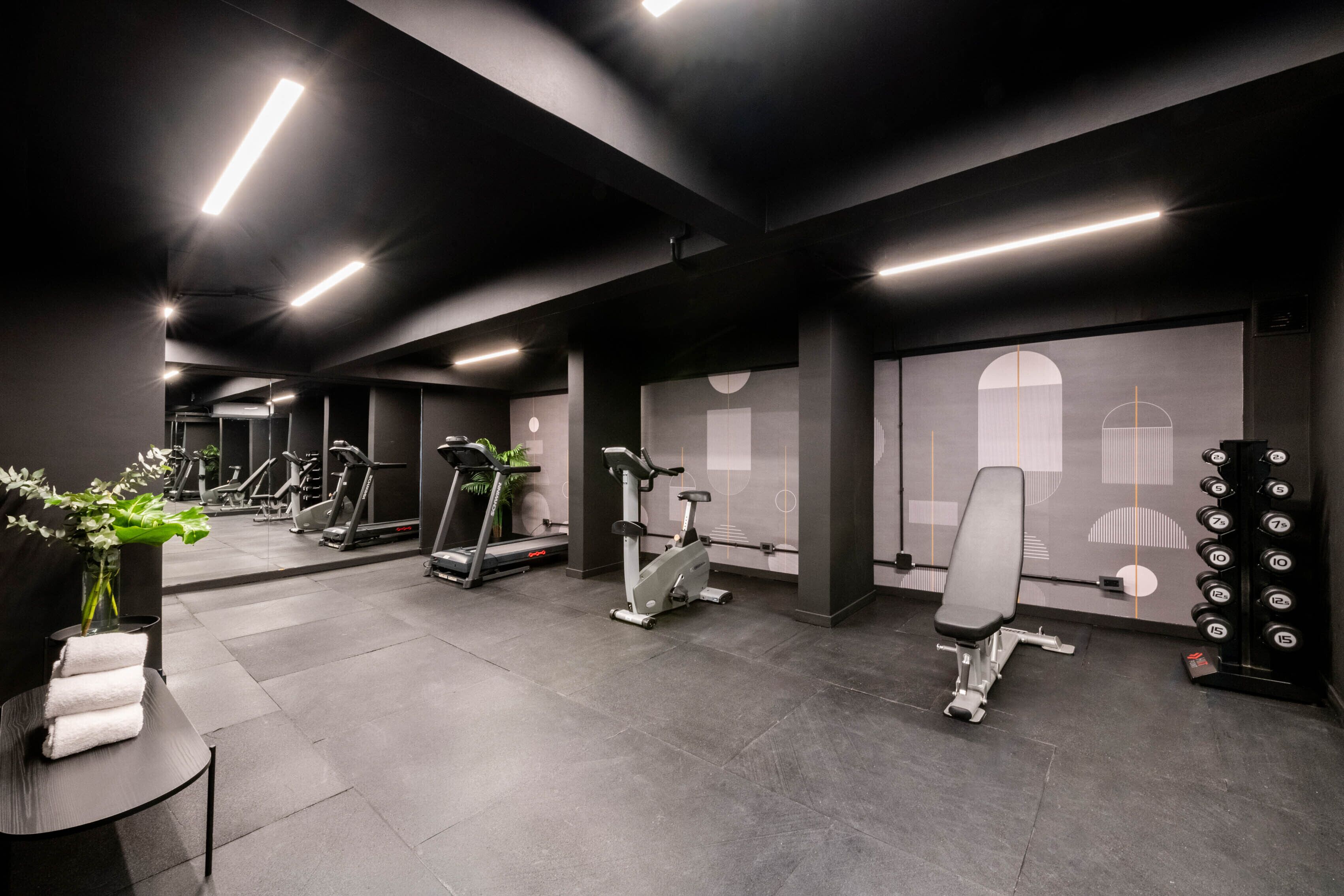 A modern gym with exercise equipment, a bench, and a wall with a geometric design.