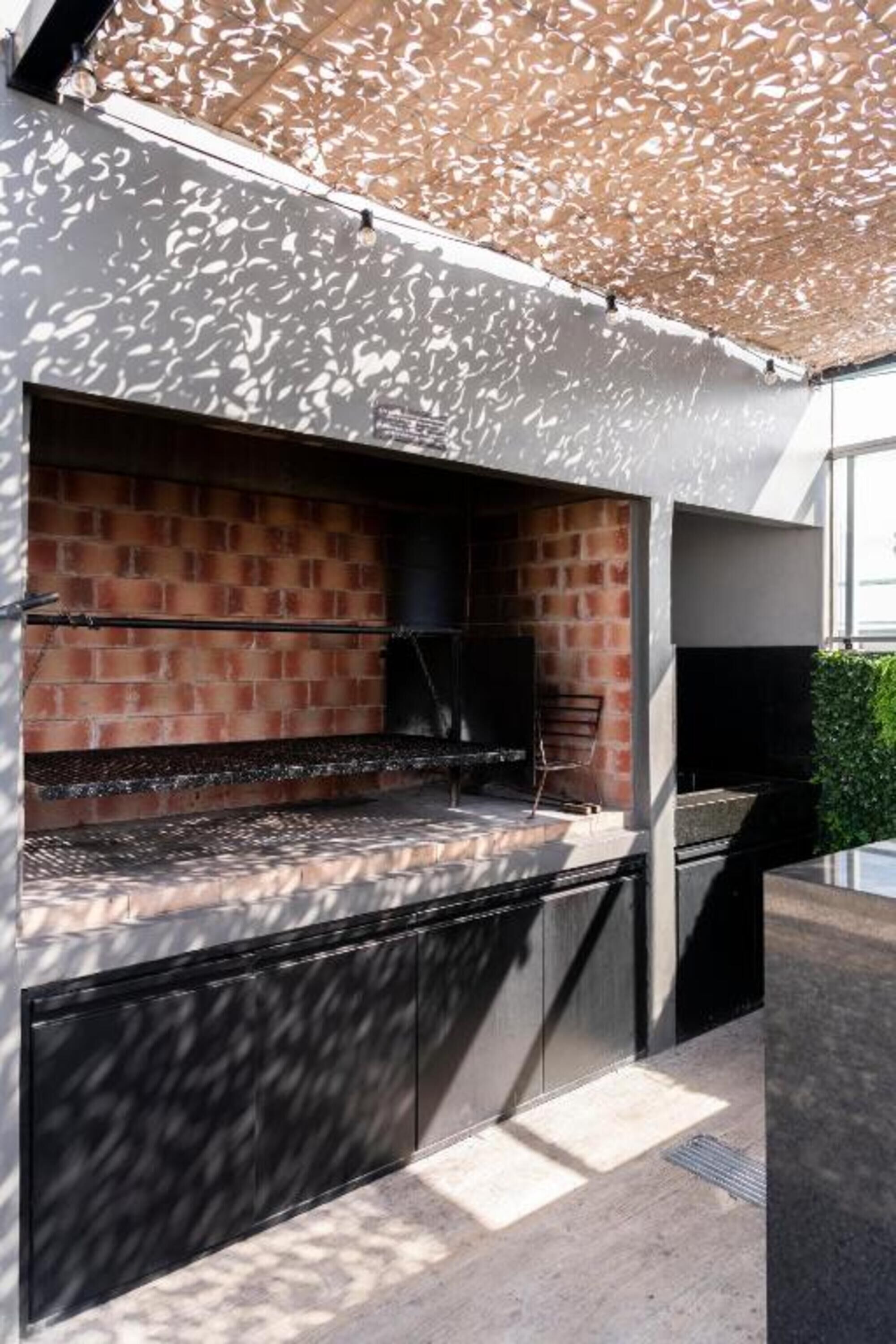 An outdoor kitchen area with a brick wall and a black countertop.