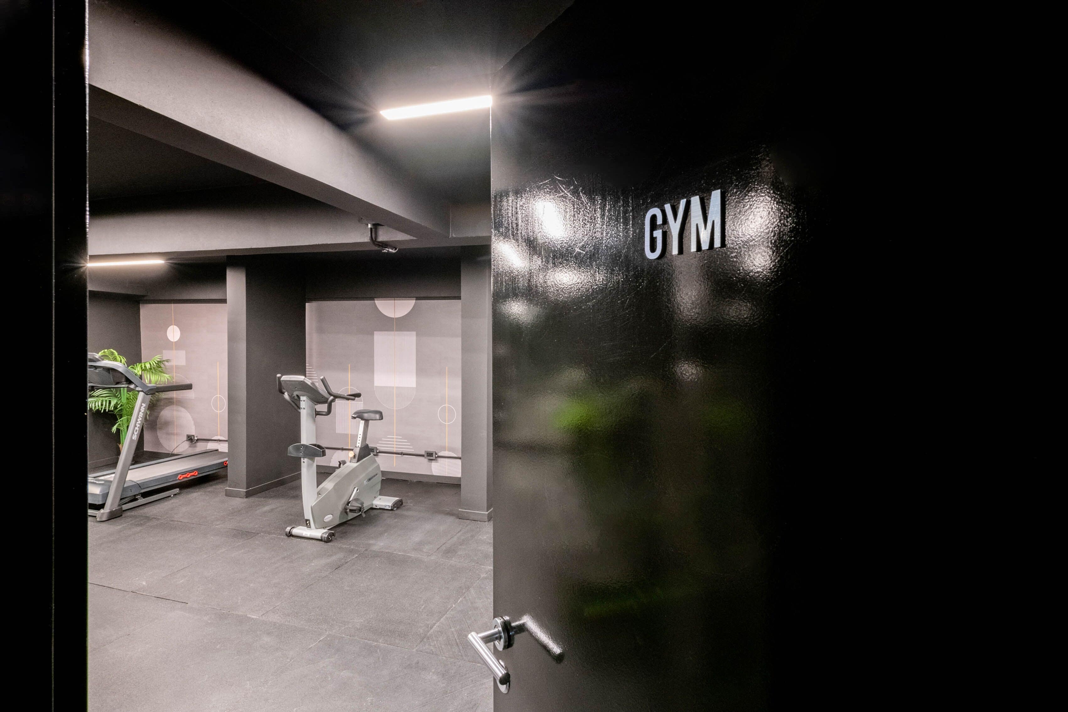A gym with exercise equipment, a treadmill, and a stationary bike.