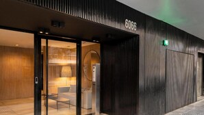 A modern building entrance with a glass door, a visible interior with a sofa and lamp, and a number '6066' on the wall. - Top Rentals Palermo Hollywood (Buenos Aires)
