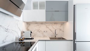 Een moderne keuken met een marmeren aanrecht, roestvrijstalen apparatuur en witte keukenkastjes.