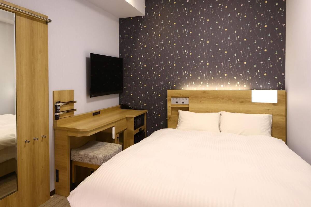 Un dormitorio con cama, escritorio, silla, armario y televisor.