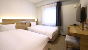 Habitación de hotel con dos camas, un escritorio, un televisor y una ventana con cortinas.