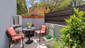 An outdoor patio with wicker chairs, a table, and potted plants.