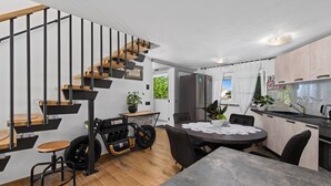 A modern kitchen with a dining area, a staircase, and a view of the outdoors.