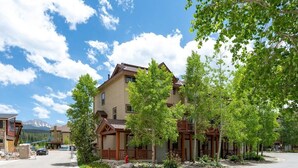 A multi-story building with a wooden facade, a front porch, and a driveway.