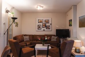 A living room with a brown sofa, a white coffee table, and a TV.
