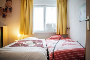 A hotel room with two beds, a window with curtains, a lamp, and a wall decoration.