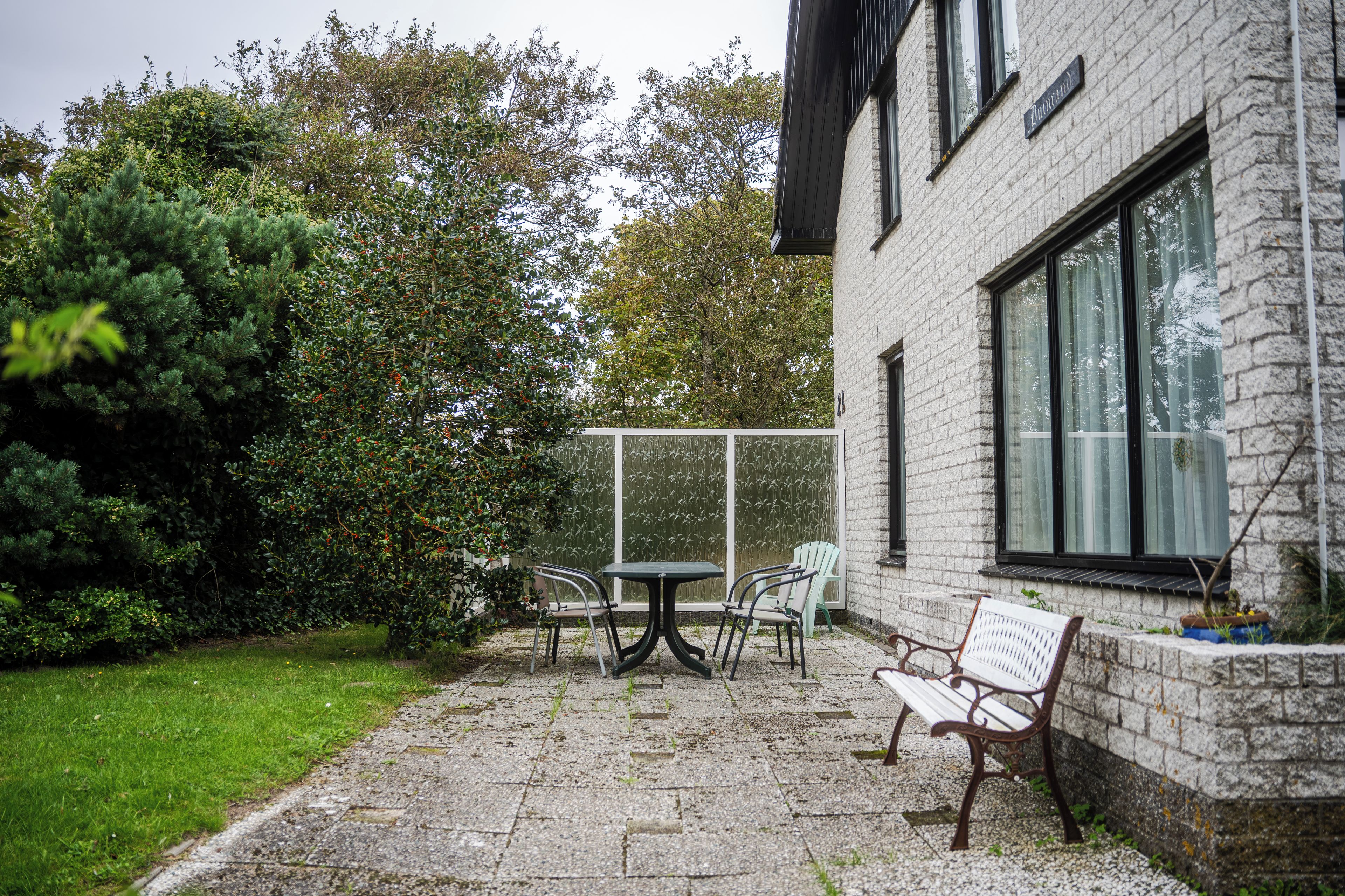 A patio with a table and chairs, a bench, and a large window.