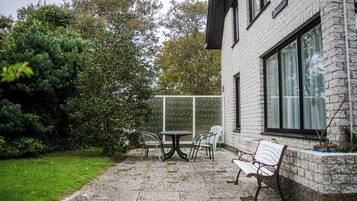A patio with a table and chairs, a bench, and a large window.